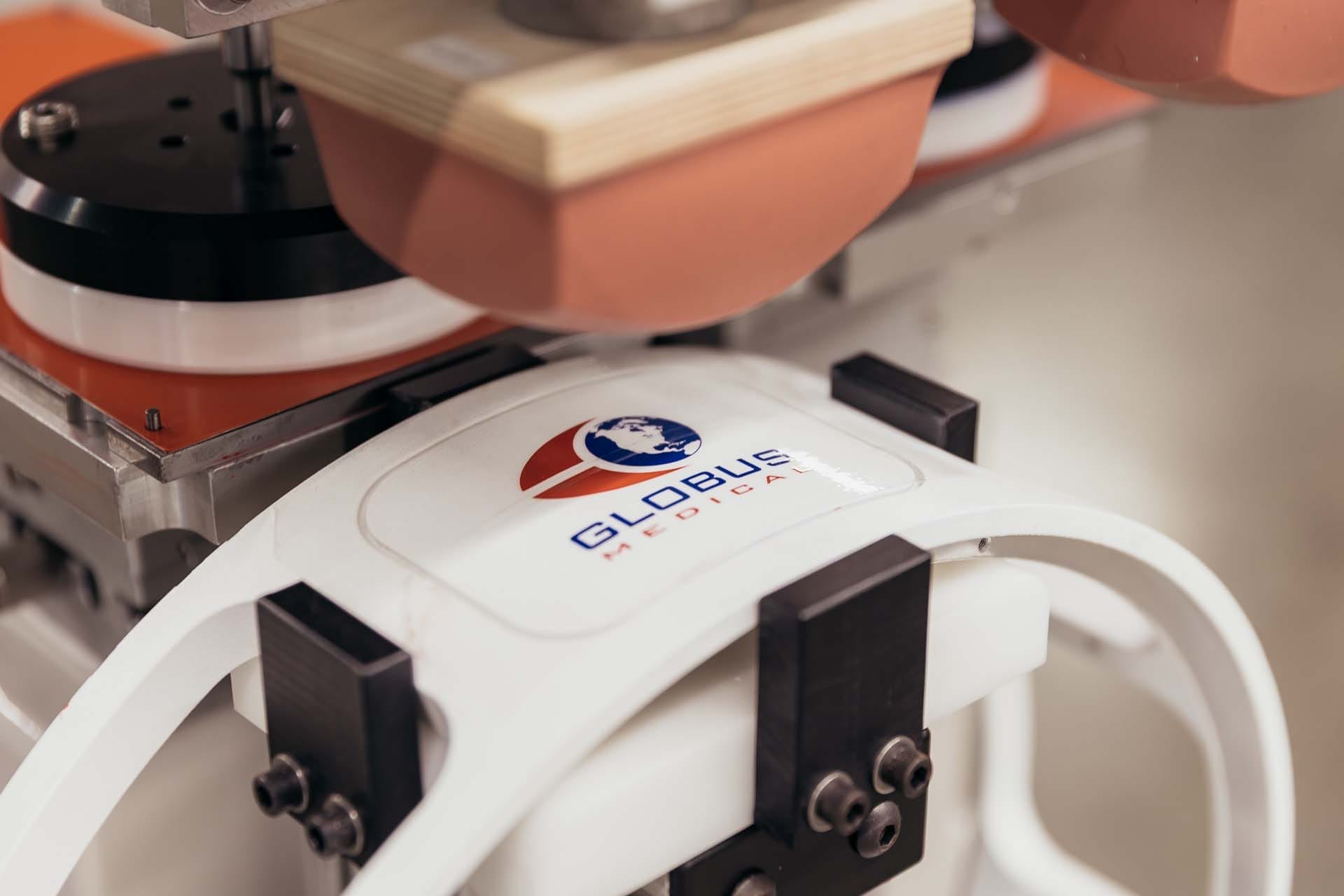 Close-up of pad printing machine transferring a logo onto a white plastic component during a custom medical device branding process.